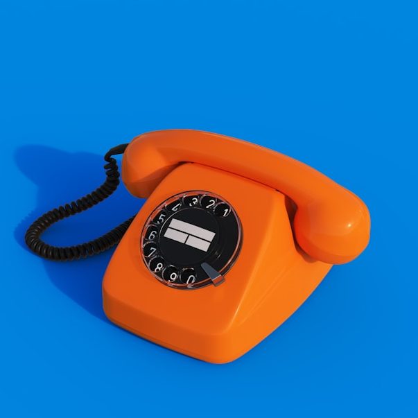 Orange Wählscheibentelefon auf blauem Hintergrund.